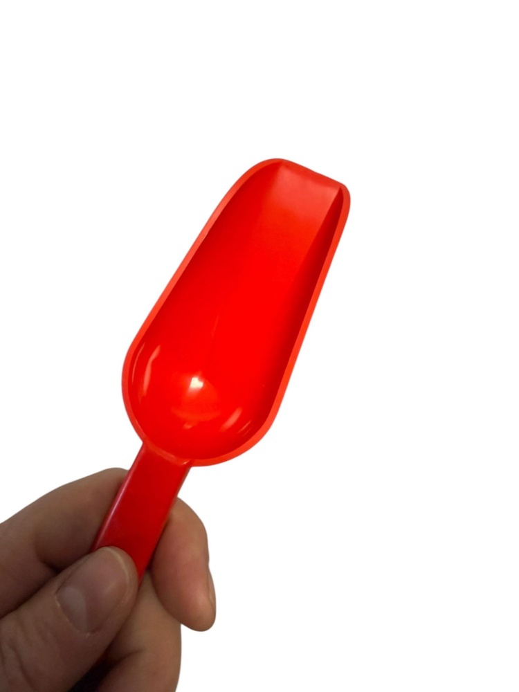 mała czerwona plastikowa szufelka do produktow supkich. Szufelka w dłoni dla pokazania jej wielkości - jest mała.